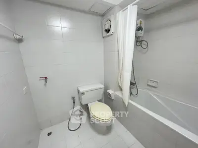 Spacious white-tiled bathroom with bathtub and modern fixtures