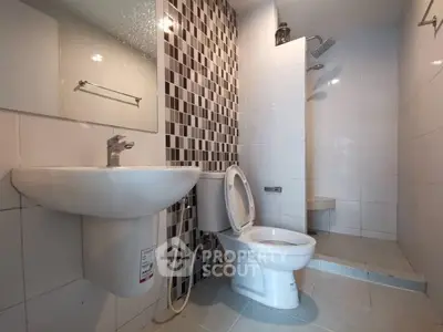 Modern bathroom with sleek fixtures and stylish tile design, featuring a shower and toilet.
