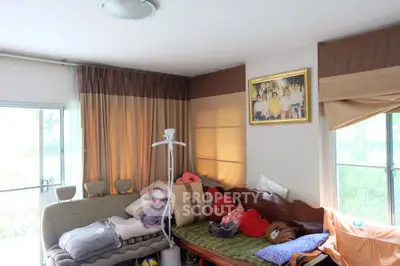 Cozy living room with natural light, featuring a comfortable sofa and large windows with curtains.