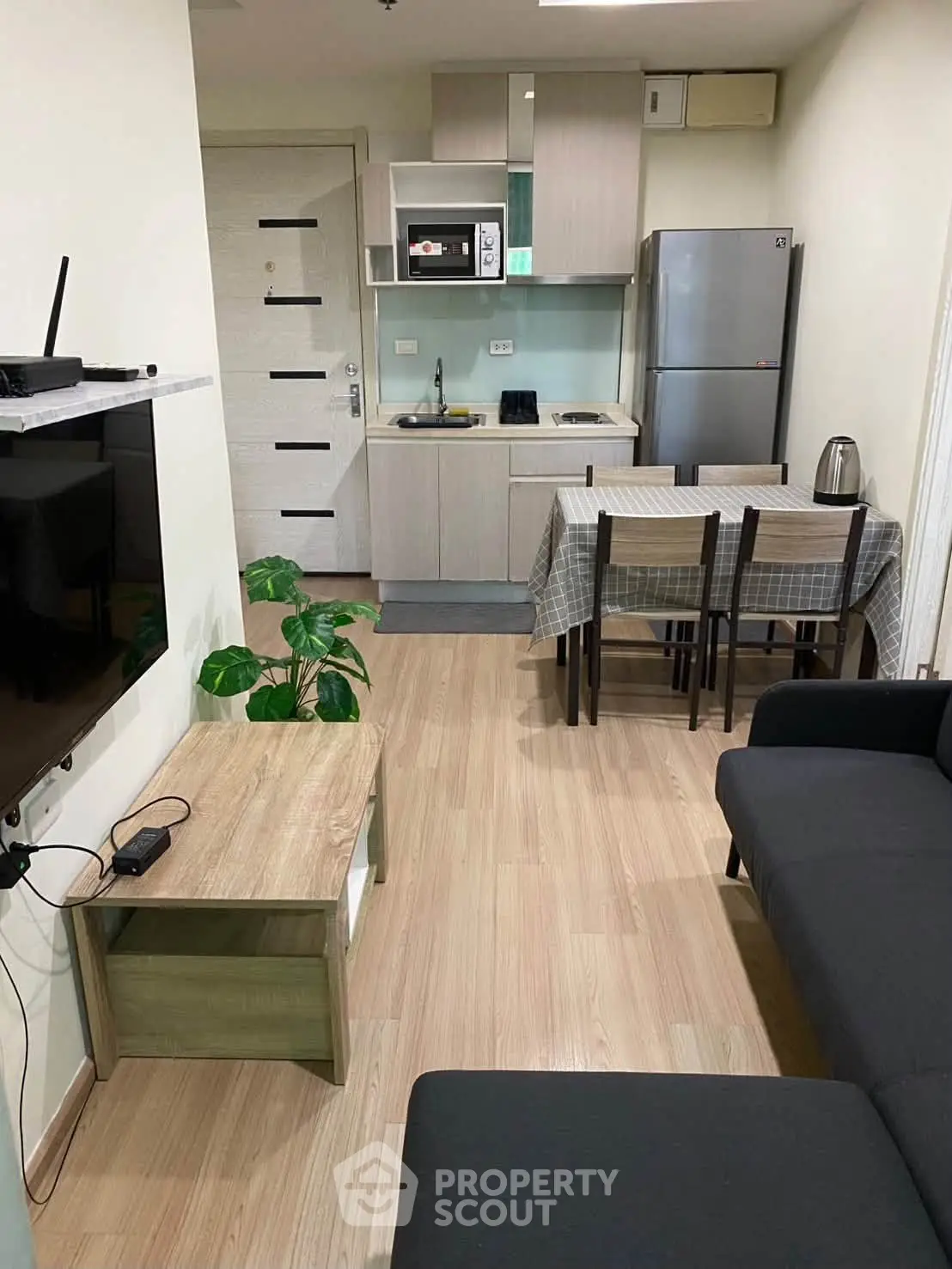 Modern open-layout living room with kitchen, featuring sleek furniture and contemporary appliances.