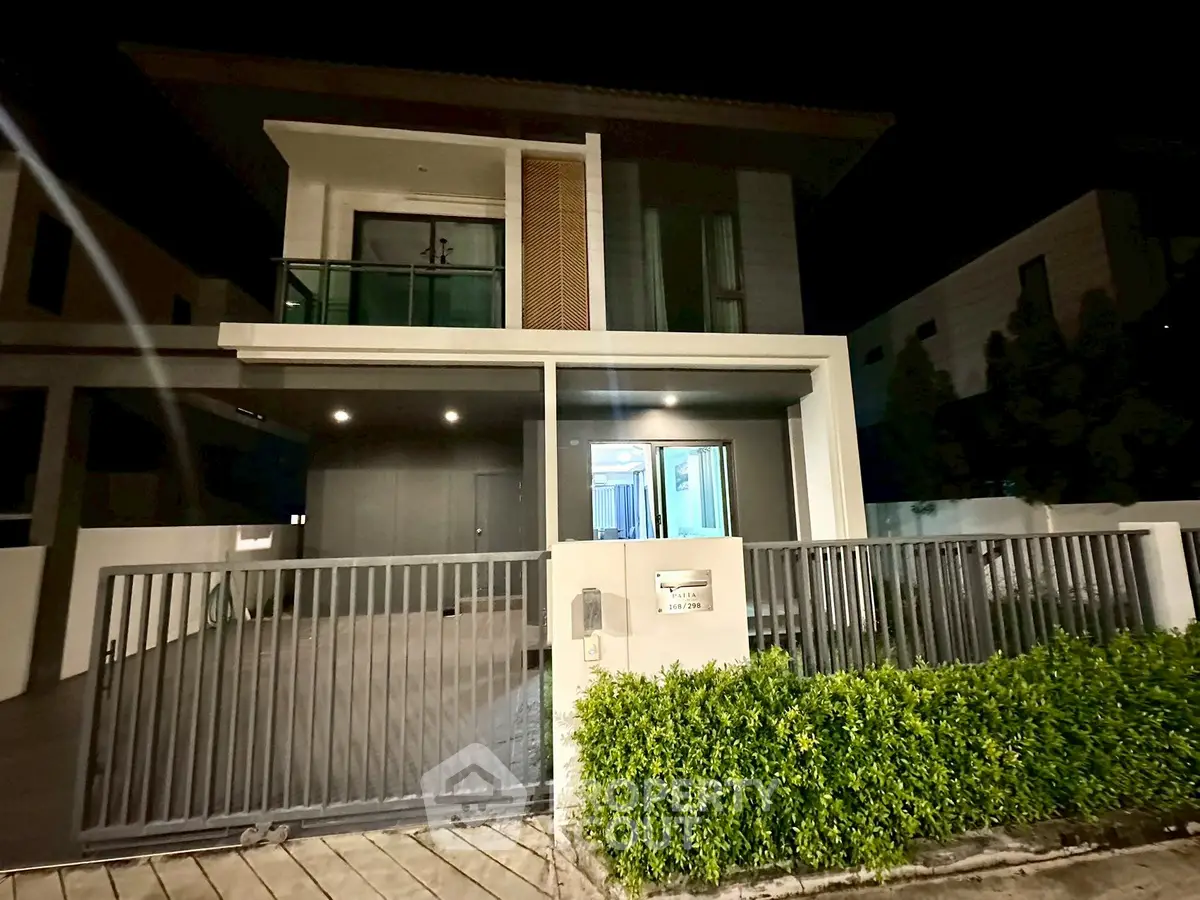 Modern two-story house with sleek design and spacious driveway at night.