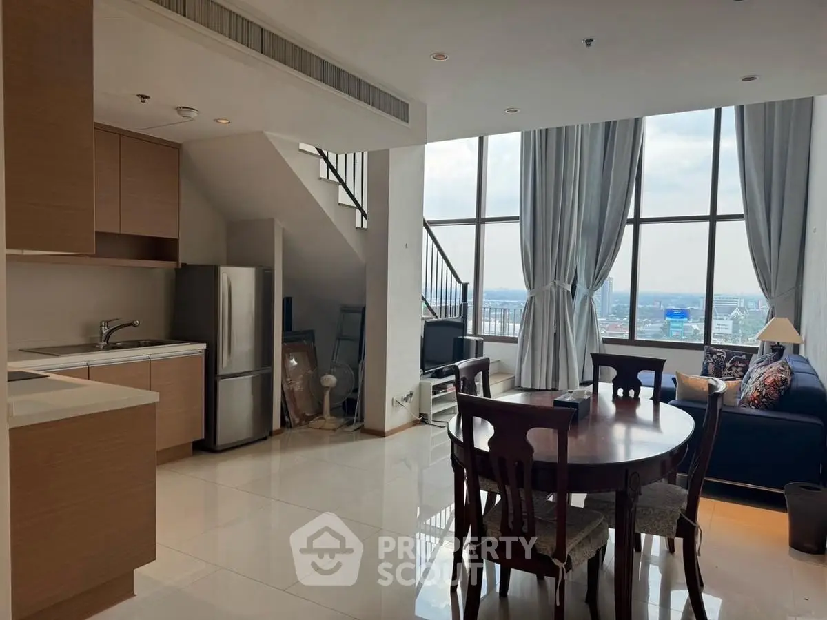 Spacious modern living room with high ceilings and city view, featuring open kitchen and elegant dining area.