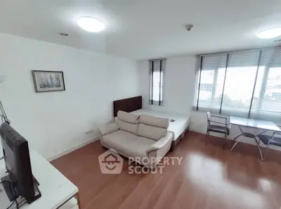 Modern studio apartment with cozy living area and large windows for natural light.