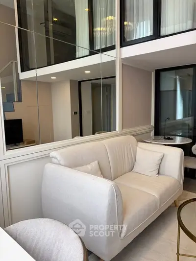 Modern living room with elegant white sofa and stylish decor in a duplex apartment.