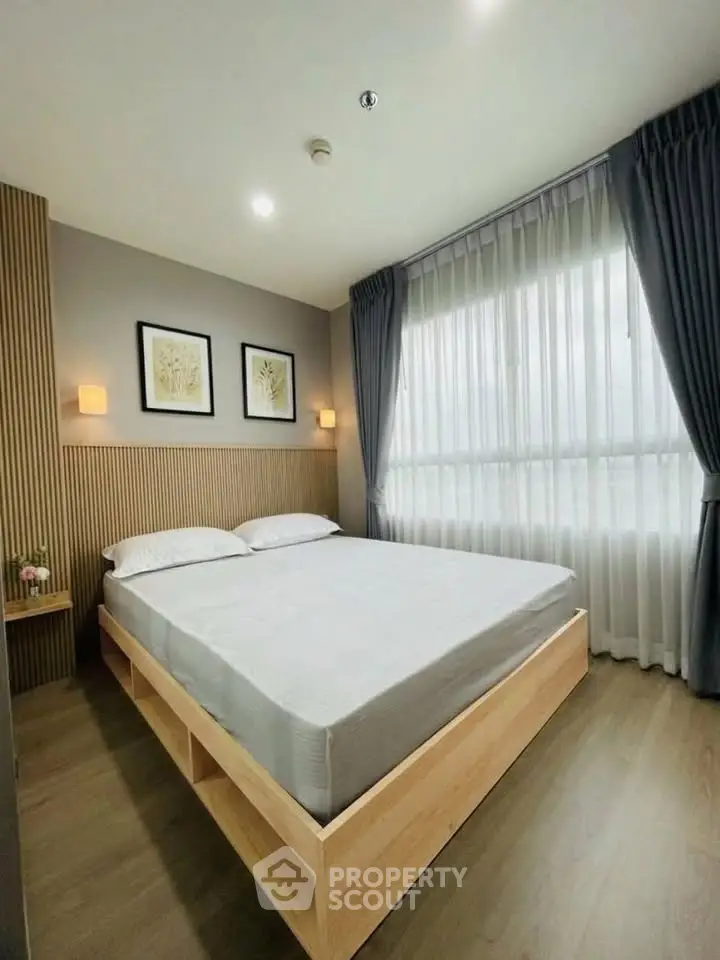 Modern bedroom with large window and stylish decor in a cozy apartment.