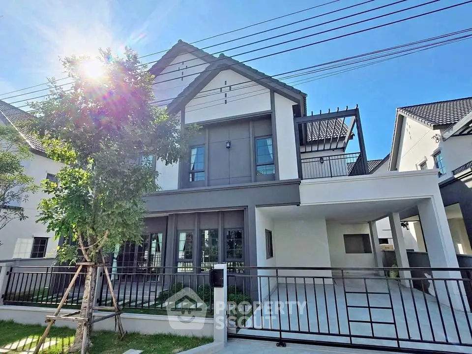 Modern two-story house with sleek design and spacious driveway under clear blue sky.
