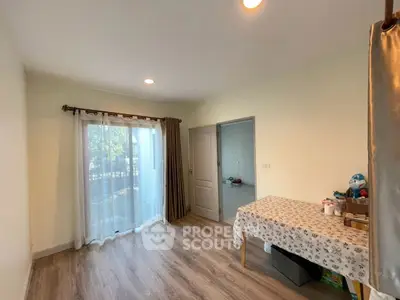 Bright room with large window and wooden floor, ideal for versatile use.