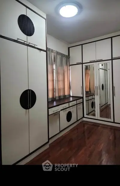 Spacious bedroom with elegant built-in wardrobes and polished wooden floors.