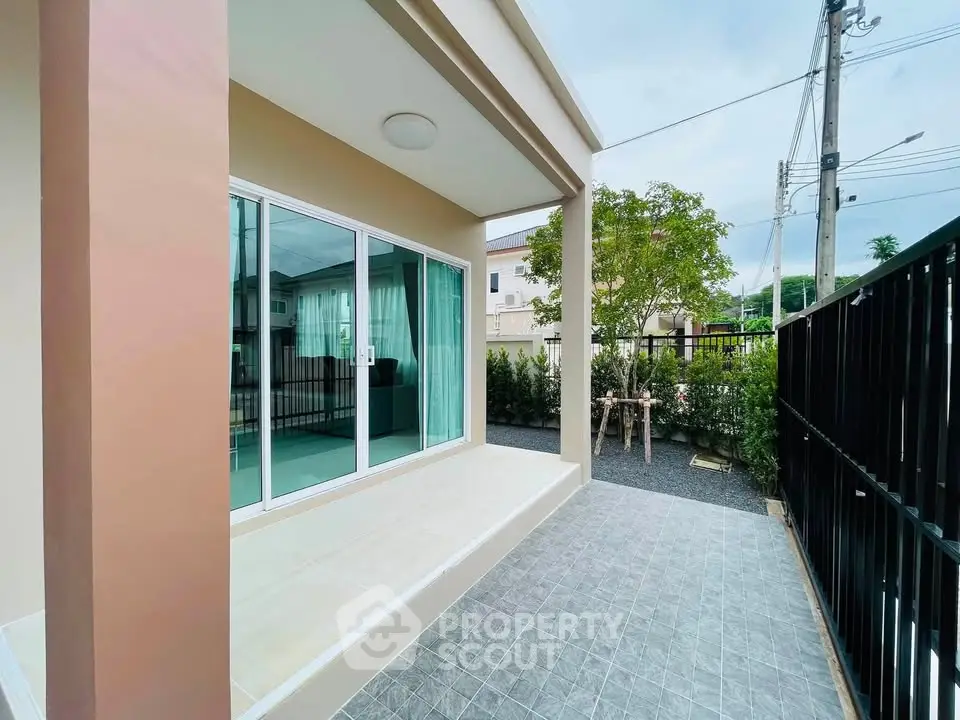 Modern home exterior with sliding glass doors and spacious tiled patio.