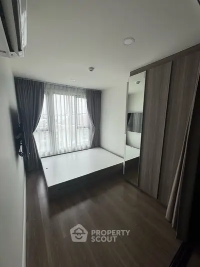 Modern bedroom with large window and sleek wardrobe in minimalist design.