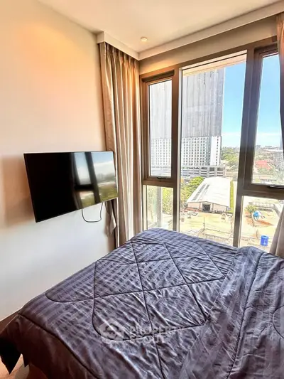 Modern bedroom with large windows and city view, featuring a wall-mounted TV and elegant bedding.