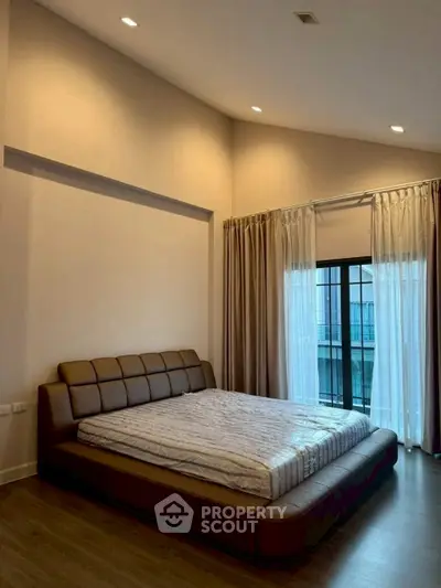 Spacious bedroom with modern design and large window for natural light.