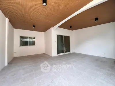 Spacious modern room with tiled floor and wooden ceiling, ideal for versatile living space.