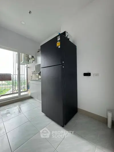 Modern kitchen with sleek black refrigerator and large windows for natural light.