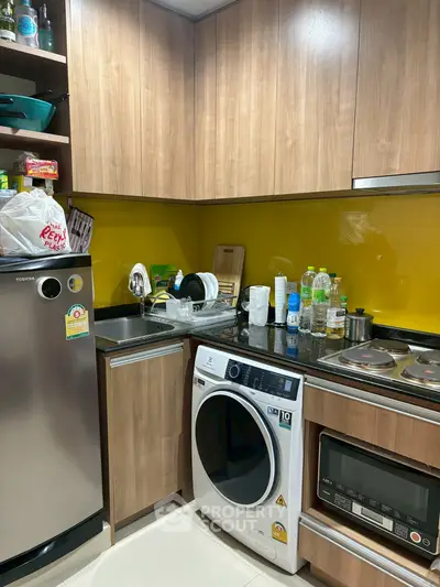 Modern kitchen with wooden cabinets, washing machine, and yellow backsplash