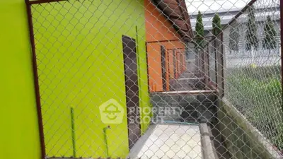 Colorful exterior of a building with chain-link fence, showcasing vibrant green and orange walls.