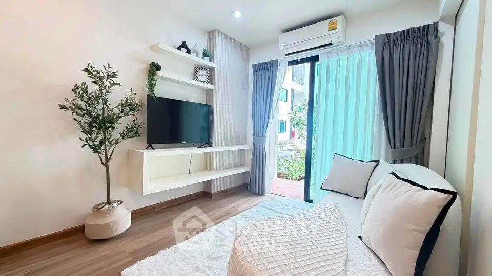 Modern living room with cozy decor and natural light, featuring a TV and stylish shelving.