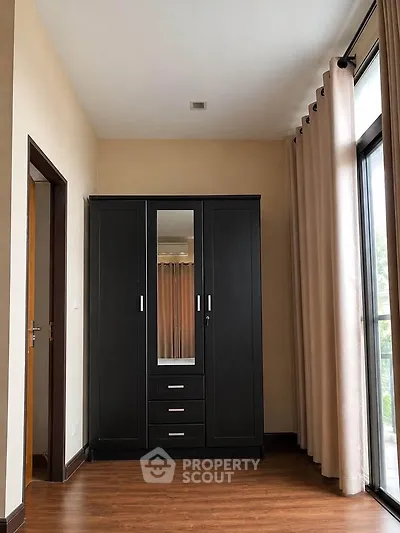 Spacious bedroom with elegant wardrobe and large window for natural light.