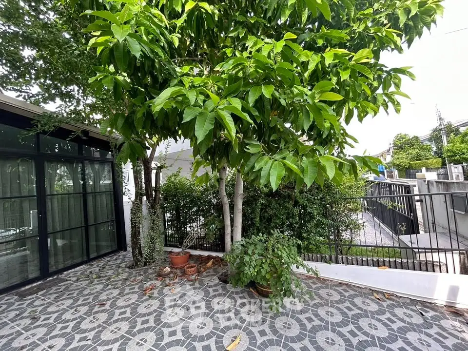 Charming garden area with lush greenery and modern tiled patio in a residential property.