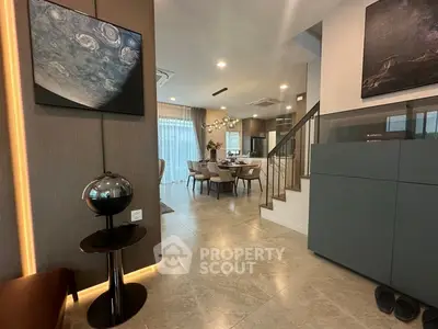 Modern open-plan living and dining area with stylish decor and staircase.