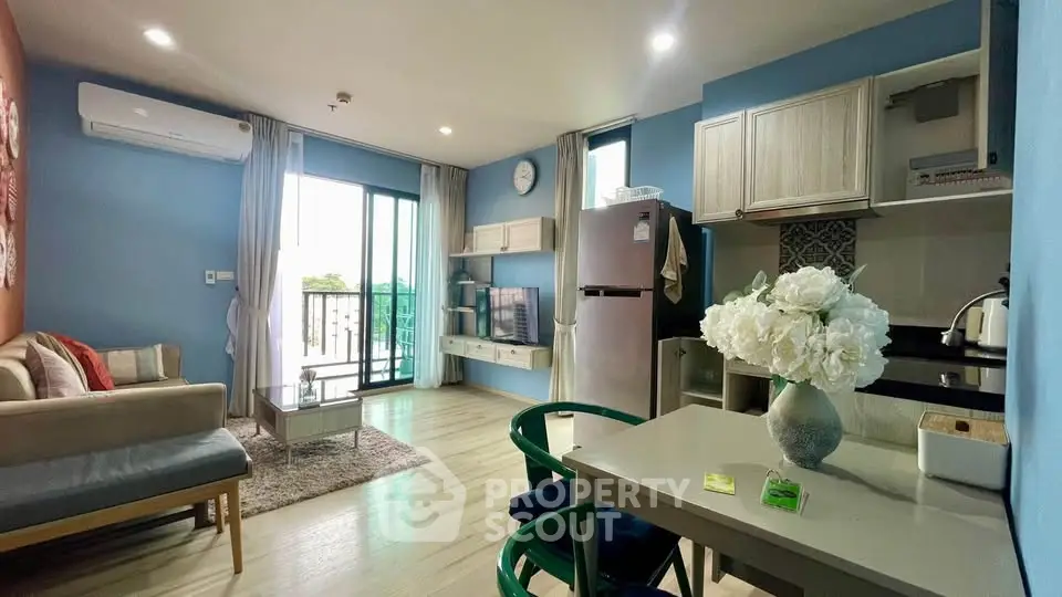 Modern living room with open kitchen, stylish decor, and balcony access in a cozy apartment.