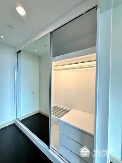 Spacious modern walk-in closet with sleek sliding doors and ample storage space.