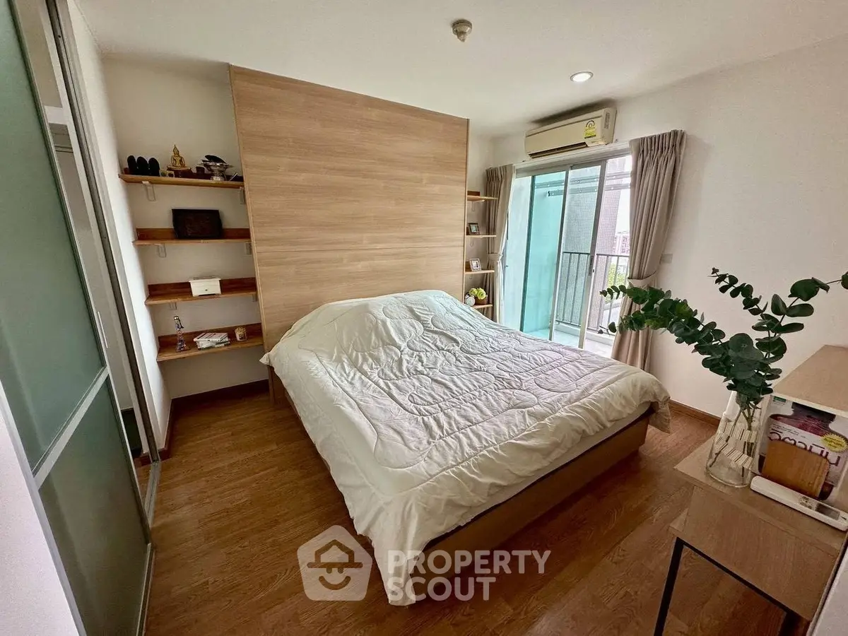 Cozy bedroom with wooden flooring and balcony access in modern apartment