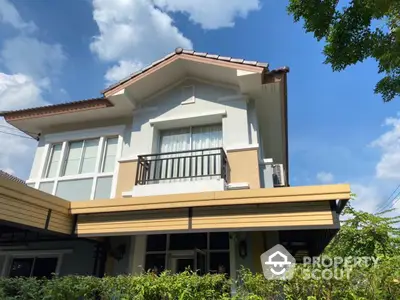 Charming two-story house with modern design and lush greenery under a clear blue sky.