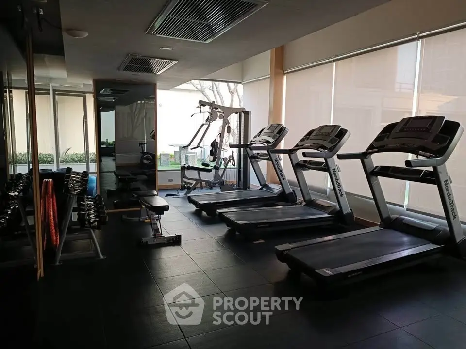 Modern gym with treadmills and weightlifting equipment in a well-lit fitness center.