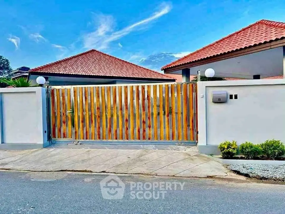 Charming suburban home with red-tiled roof and modern wooden gate, perfect for family living.