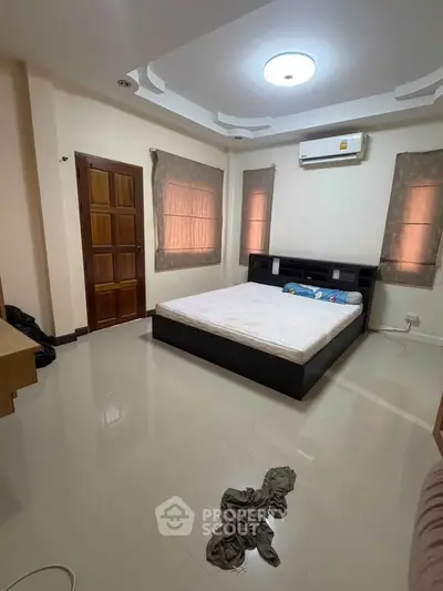 Spacious bedroom with modern design and ample natural light, featuring a comfortable bed and stylish decor.