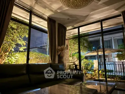 Luxurious living room with large windows and garden view at night