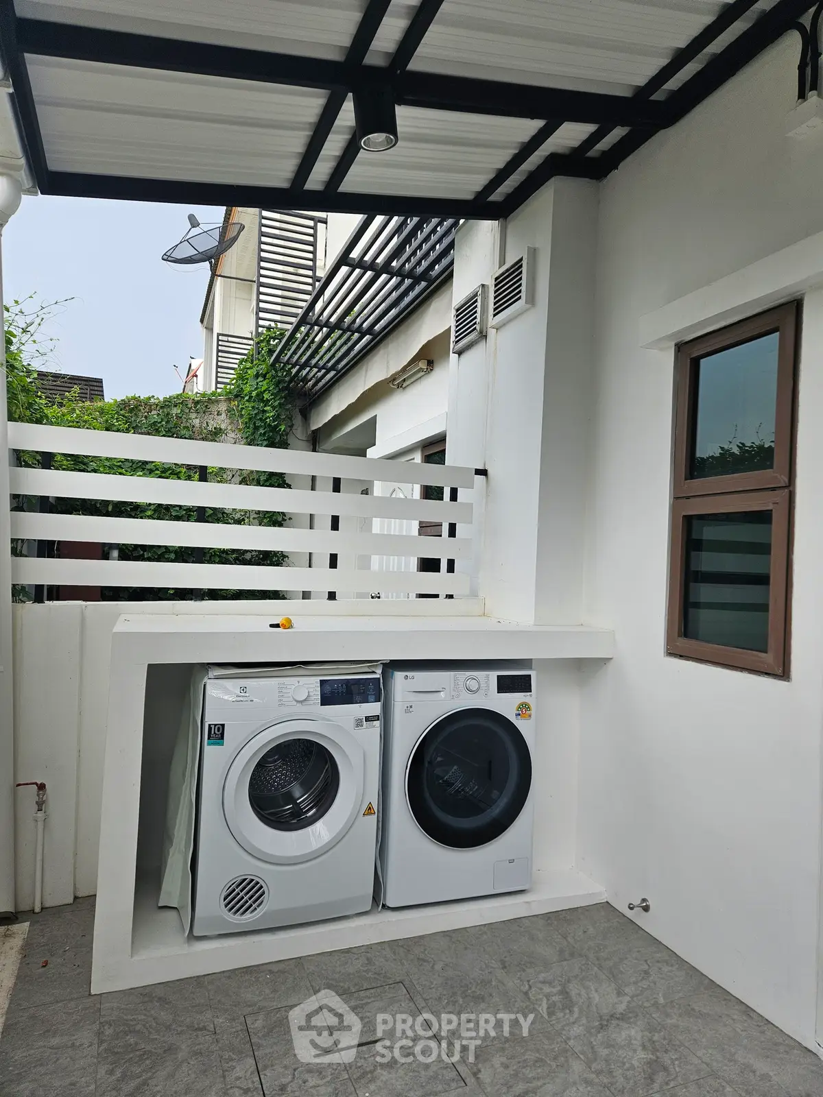 Modern outdoor laundry area with washing machine and dryer in a stylish residential setting.
