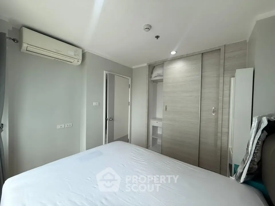 Modern bedroom with built-in wardrobe and air conditioning in a stylish apartment.