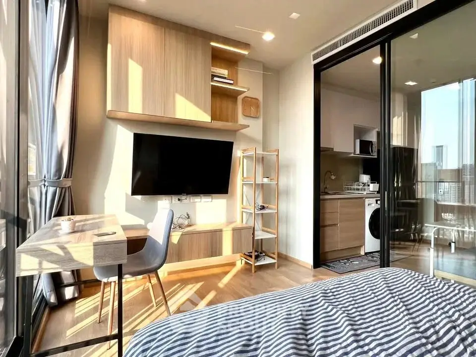 Modern studio apartment with open layout, featuring a cozy living area, kitchen, and large windows.