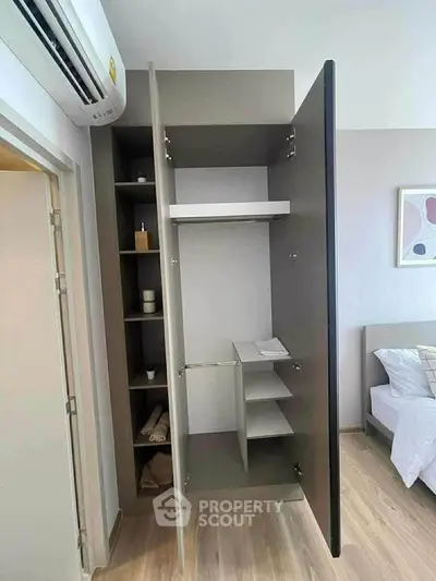 Modern bedroom with open wardrobe and air conditioning, showcasing sleek design and functionality.