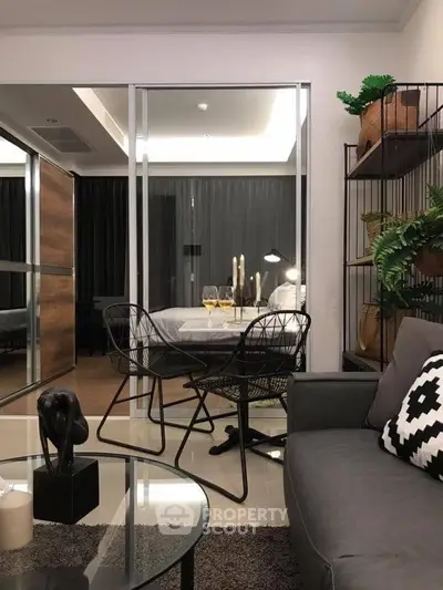 Modern living room with stylish decor and glass partition leading to bedroom, featuring elegant furniture and ambient lighting.