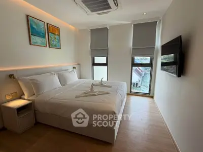 Modern bedroom with stylish decor and natural light, featuring a cozy bed and wall-mounted TV.