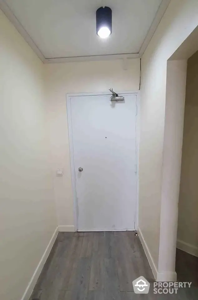 Minimalist entrance hallway with white door and wooden flooring