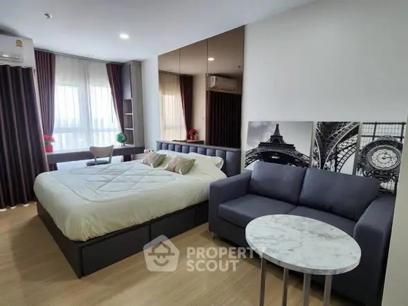 Modern bedroom with stylish decor and cozy seating area in a well-lit apartment.