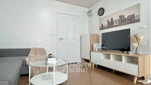 Modern living room with sleek furniture and stylish decor, featuring a cozy gray sofa and a flat-screen TV.