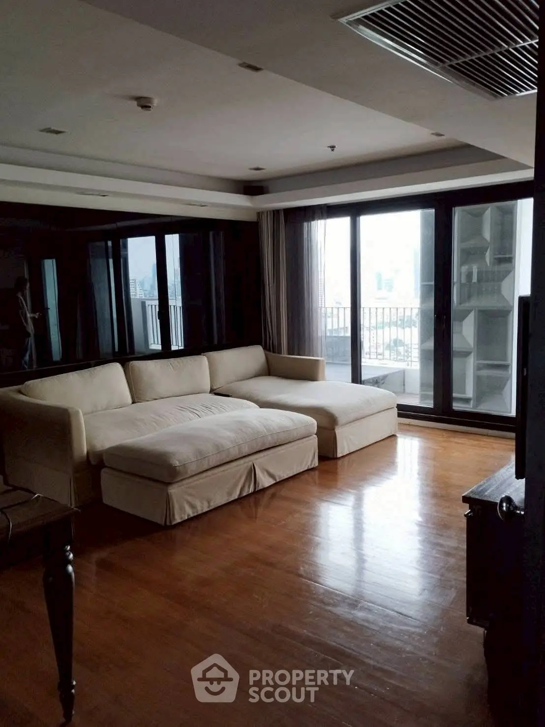 Spacious living room with large windows and city view, featuring a comfortable sectional sofa.