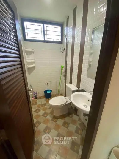 Compact bathroom with modern fixtures and tiled walls, featuring a shower and window for natural light.