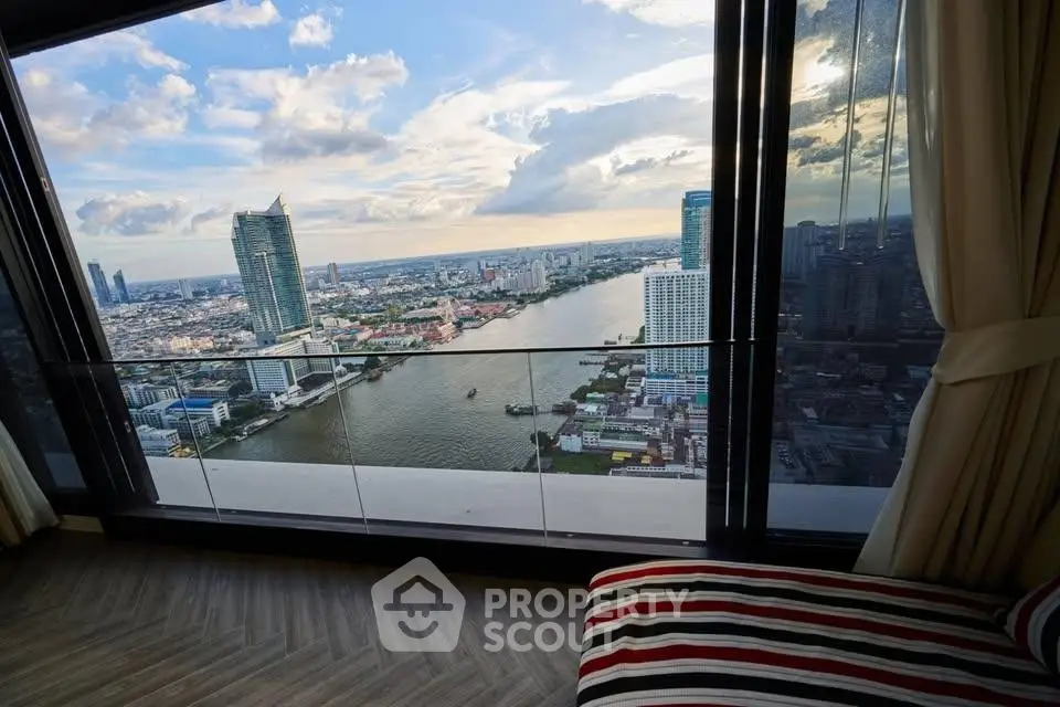 Stunning high-rise apartment view overlooking a river and cityscape, featuring floor-to-ceiling windows.