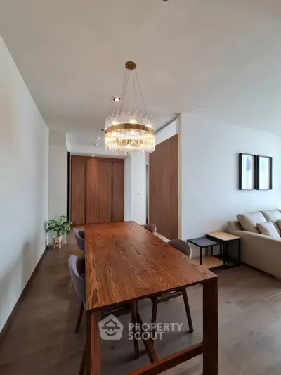 Elegant dining area with wooden table and modern chandelier in a stylish living room.