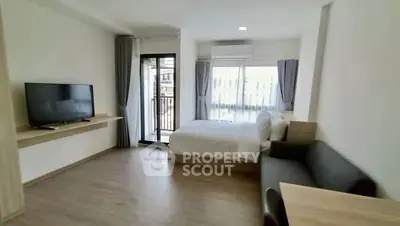 Spacious modern studio apartment with large windows and balcony access.