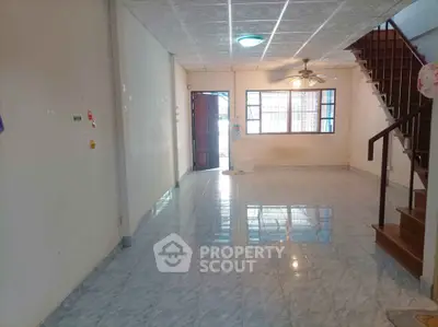 Spacious living room with tiled flooring and staircase in a bright home