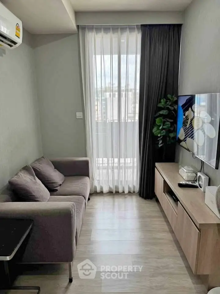 Modern living room with cozy sofa, sleek TV unit, and large window for natural light.