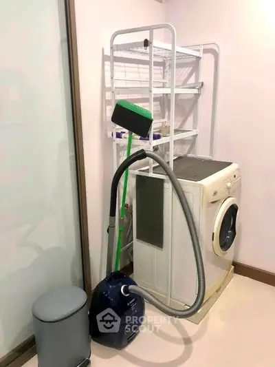 Compact laundry area with washing machine and storage rack in modern apartment.