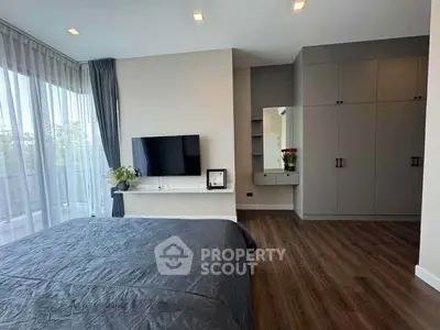 Modern bedroom with large windows and stylish decor, featuring a wall-mounted TV and spacious wardrobe.